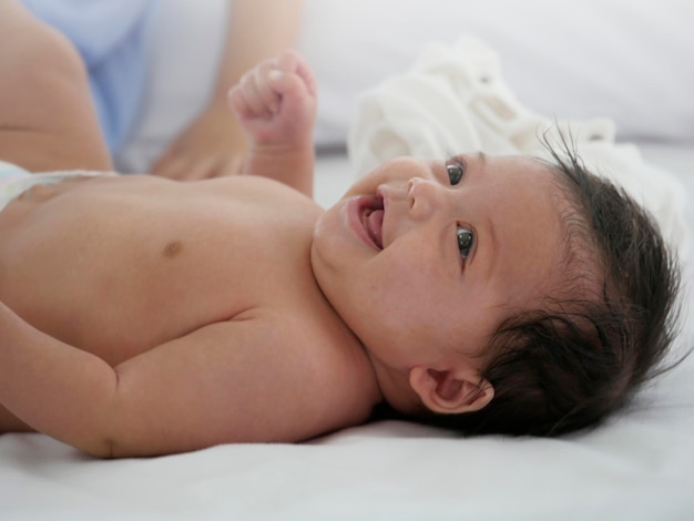 Photo heureux petit bébé souriant en position couchée dans son lit enfant souriant bonne émotion