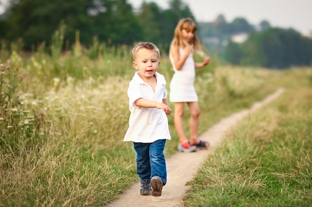 Heureux petit enfant courant sur la route à la campagne au coucher du soleil