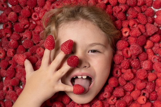 Heureux petit enfant face à la framboise enfant cueillant des framboises les enfants cueillent des fruits frais sur une râpe bio