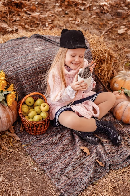 Heureux petit enfant fille avec mignon hérisson Portrait d'enfant avec animal de compagnie dans la nature d'automne avec des citrouilles et de la paille tenant une tasse de boisson chaude