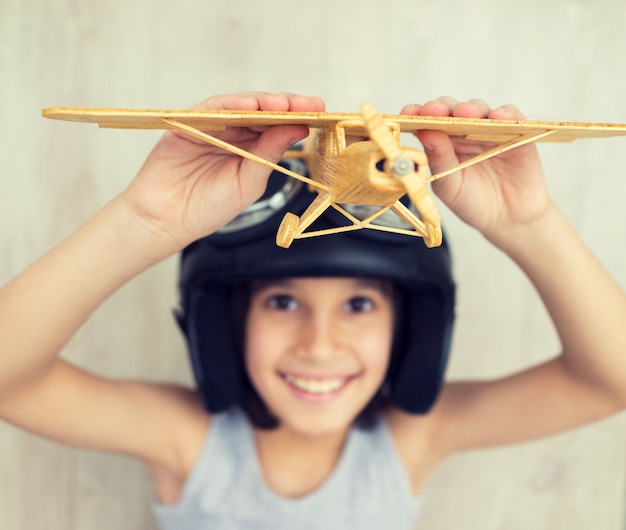 Heureux petit enfant jouant avec un avion en bois