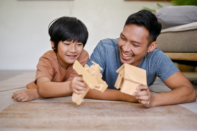 Heureux petit garçon asiatique jouant un modèle de figurine en bois avec son père