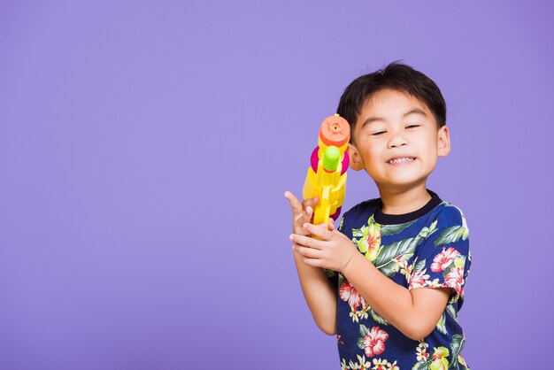 Heureux petit garçon asiatique tenant un pistolet à eau en plastique, jour du festival de Songkran en Thaïlande