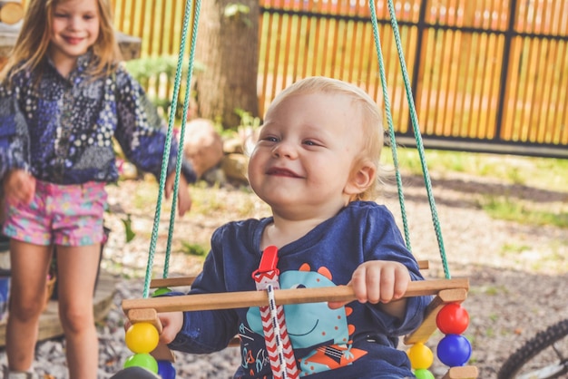 L'heureux petit garçon sur une balançoire à l'extérieur