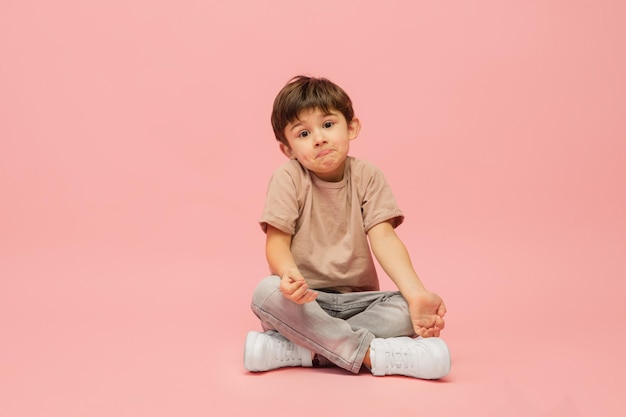 Heureux petit garçon caucasien isolé sur fond de studio rose a l'air heureux joyeux sincère Copyspace concept d'émotions de l'éducation de la petite enfance