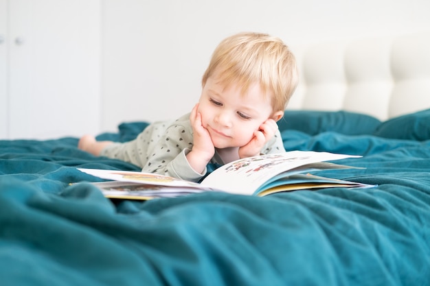 Heureux Petit Garçon Drôle En Pyjama Livre De Lecture Couché Dans Le Lit De Ses Parents