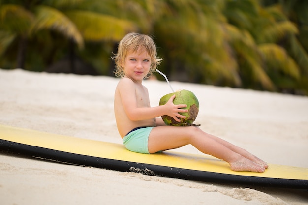 Heureux petit garçon enfant d'âge préscolaire drôle, boire du jus de noix de coco sur la plage de l'océan.