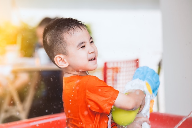 Heureux petit garçon enfant asiatique s&#39;amuser à jouer de l&#39;eau avec un pistolet à eau et à Songkran festi