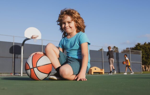 Heureux petit garçon enfant jouant au basket sur l'aire de jeux