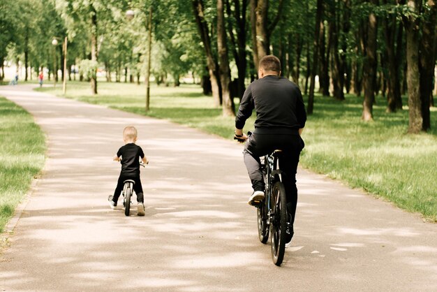 Heureux petit garçon fait du vélo avec un jeune papa dans le parc