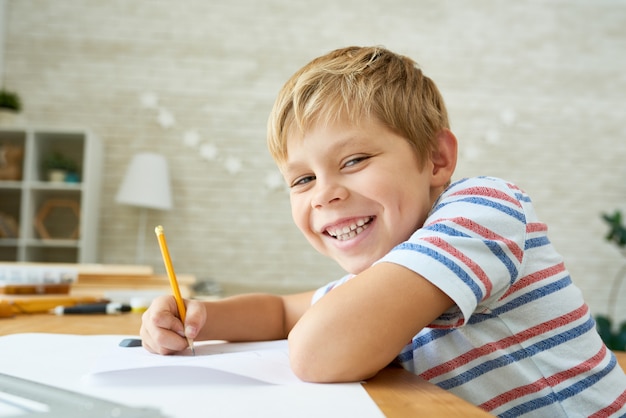 Heureux petit garçon fait ses devoirs