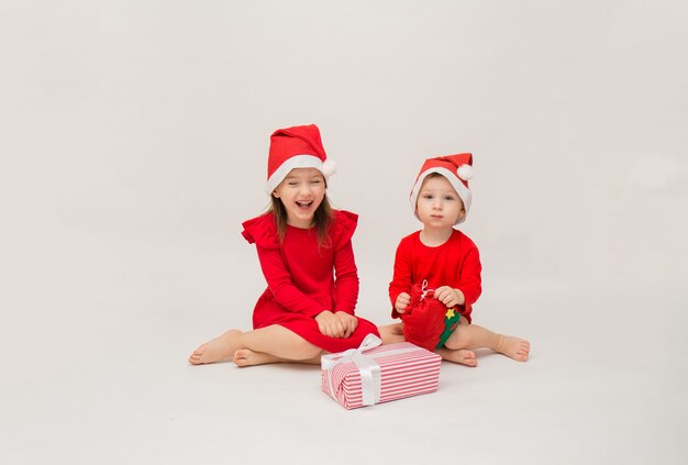 Heureux petit garçon et fille en bonnets rouges sur blanc