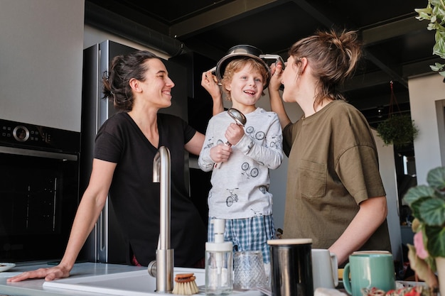 Heureux petit garçon jouant dans la cuisine avec ses mères homosexuelles