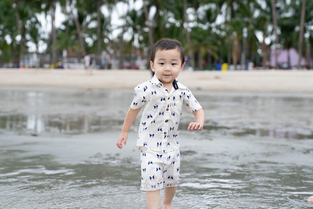 Heureux petit garçon jouant sur le sable avec la plage d'été de la mer