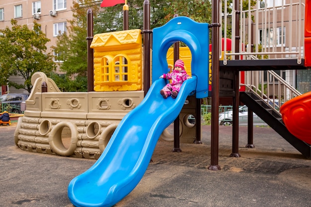 Heureux petit garçon jouant sur un toboggan dans une aire de jeux