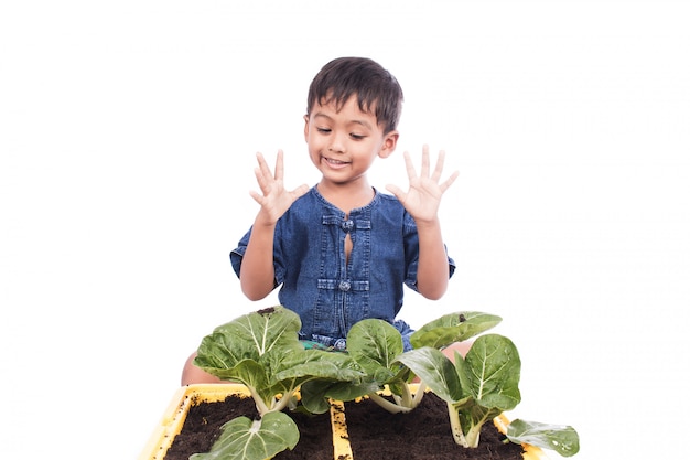 Heureux petit garçon mignon avec des légumes verts en pot