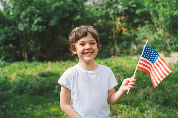 Photo heureux petit garçon patriotique tenant le drapeau américain les états-unis célèbrent le 4 juillet joyeuse fête de l'indépendance