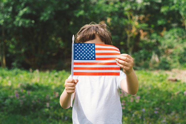 Heureux petit garçon patriotique tenant le drapeau américain Les États-Unis célèbrent le 4 juillet Joyeuse fête de l'indépendance