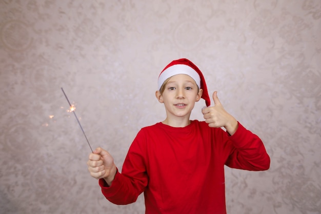 Heureux petit garçon portant bonnet de Noel et tenant sparkler, réveillon du nouvel an