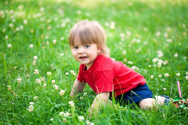 Heureux petit garçon rampant dans l'herbe