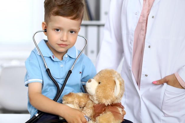 Heureux petit patient après examen de santé Petit médecin examinant un ours en peluche avec stéthoscope