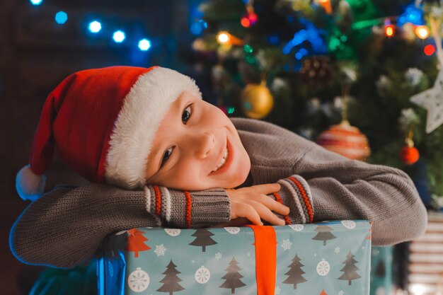 Heureux petits enfants de garçon en bonnet de noel avec cadeau ont Noël ou le nouvel an.