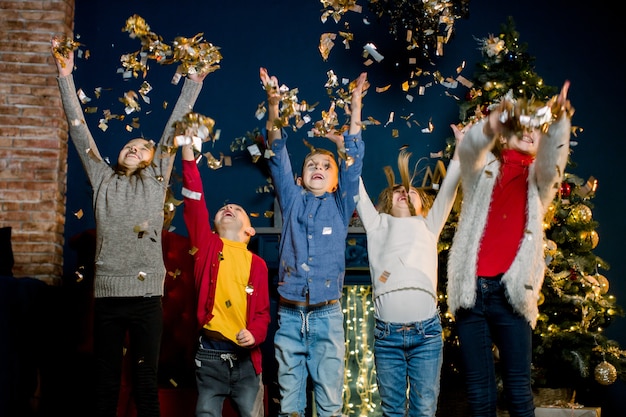 Heureux petits enfants lancent des confettis et célèbrent Noël