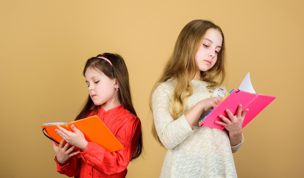 Heureux petits enfants prêts pour la leçon d'école élèves lisant un livre Projet scolaire Cahiers d'exercices d'amitié et de fraternité pour l'écriture Retour à l'école petites filles avec des carnets de notes Découvrir la guérison