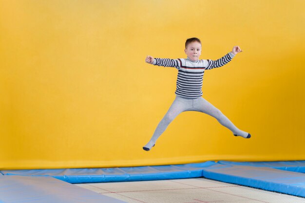 Heureux petits enfants souriants sautant sur un trampoline à l'intérieur dans un centre de divertissement