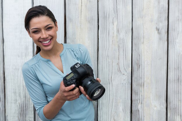 Heureux photographe féminin debout sur fond de bois