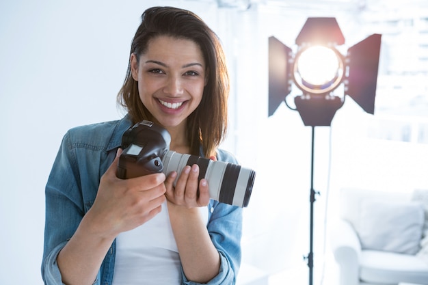 Heureux photographe féminin debout en studio