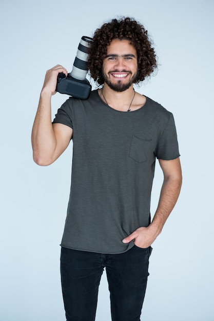 Heureux photographe tenant un appareil photo dans le studio