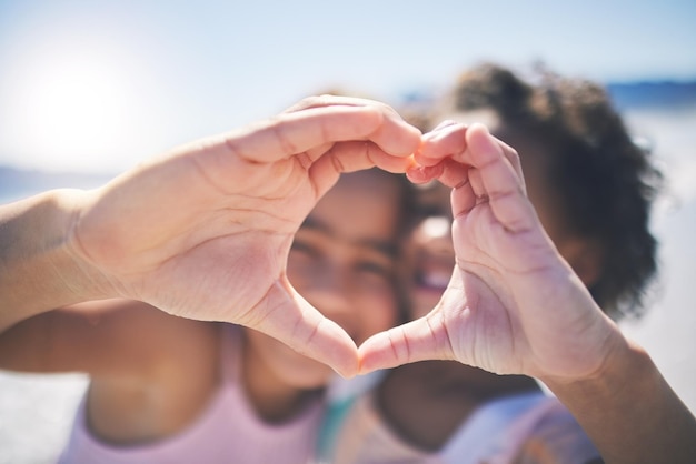 Heureux en plein air et filles avec soutien des mains du cœur et bien-être pendant la pause se détendre ou se lier Amis jeunes ou enfants avec symbole de bonheur pour l'amour ou emoji avec soin solidarité ou à l'extérieur