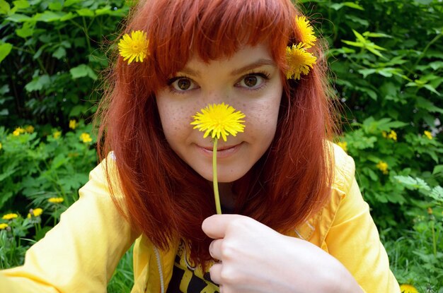 Heureux portrait d'une jeune fille aux cheveux roux avec des taches de rousseur avec fleur de pissenlit