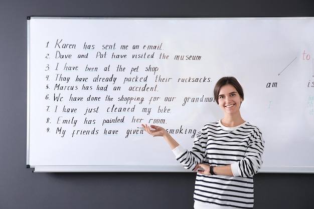 Photo heureux professeur d'anglais près du tableau blanc à la leçon