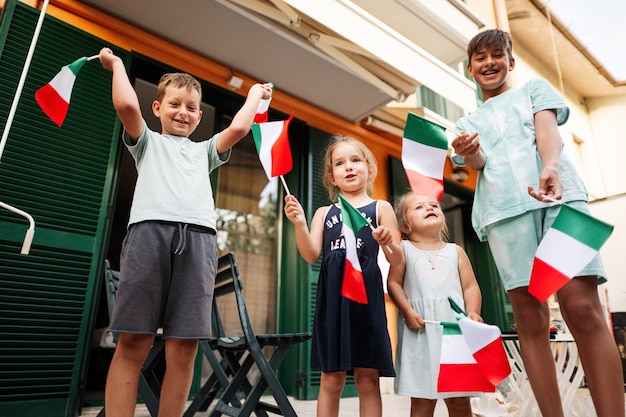 Heureux quatre enfants avec des drapeaux italiens célébrant la fête de la République d'Italie