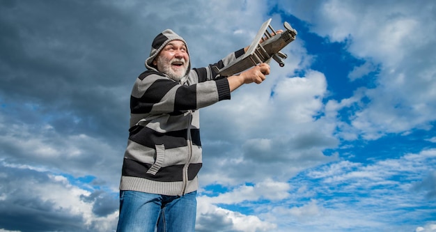Heureux retraité senior homme mûr à la retraite vieil homme haut sur fond de ciel avec avion jouet