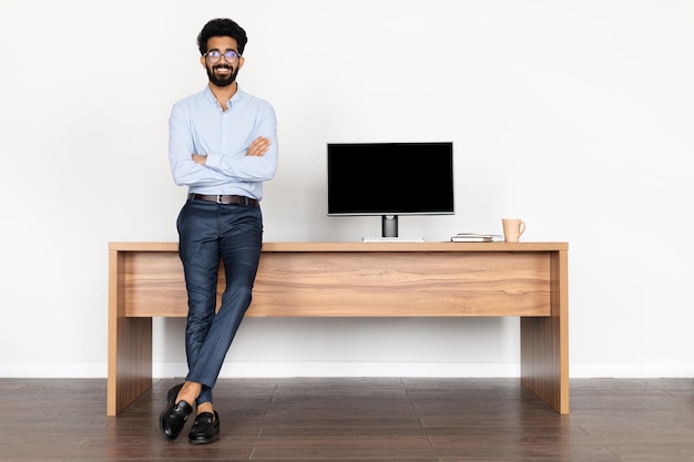 Heureux réussi bel homme moyen-oriental posant au bureau