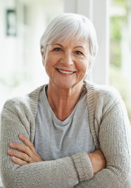 Heureux de savoir que j'ai planifié ma retraite Une femme senior heureuse souriant à la caméra alors qu'elle est assise dans sa maison