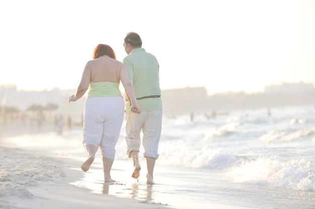 heureux senior couple de personnes âgées matures ont du temps romantique sur la plage au coucher du soleil