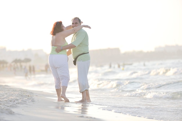 heureux senior couple de personnes âgées matures ont du temps romantique sur la plage au coucher du soleil