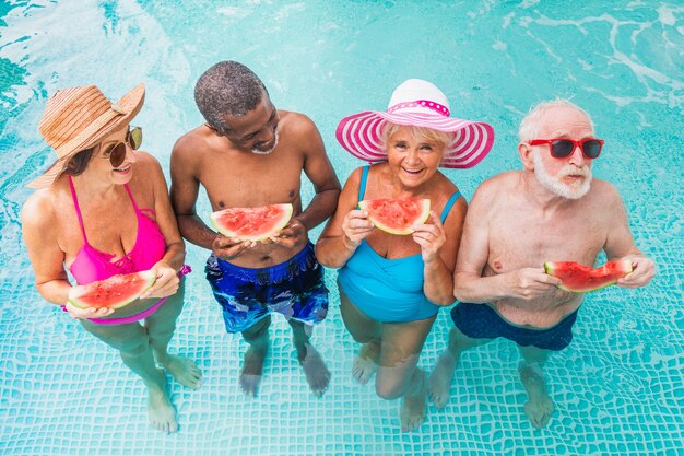 Heureux seniors faisant la fête dans la piscine Amis âgés lors d'une fête au bord de la piscine en été