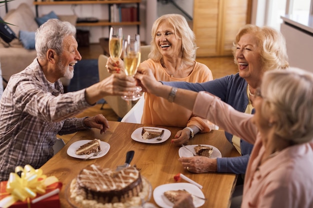 Heureux les seniors s'amusant tout en célébrant l'anniversaire et en portant un toast au champagne