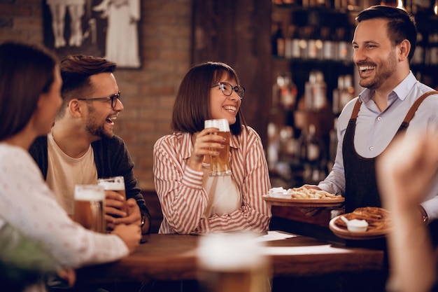 Heureux serveur s'amusant avec son client tout en lui servant de la nourriture dans un bar