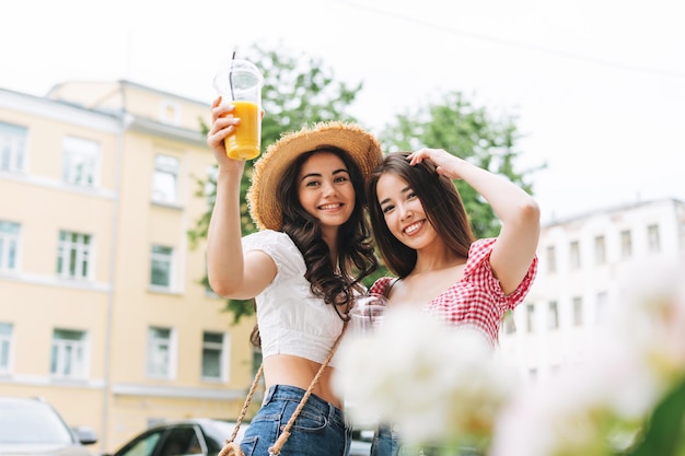 Heureux souriant belle brune jeunes femmes amis en vêtements d'été avec du jus dans les mains