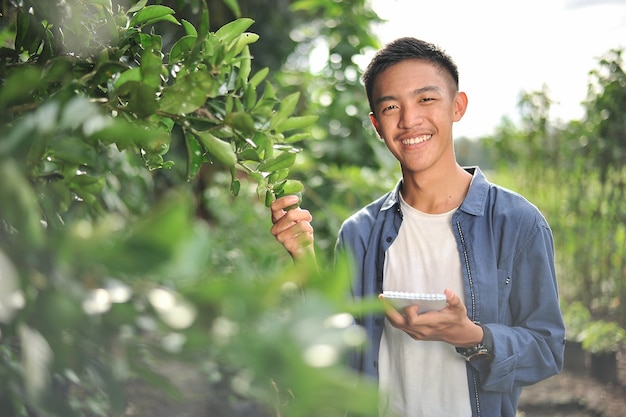 Heureux de sourire jeune agriculteur asiatique tenant le cahier sur jardin verdoyant, sur place.