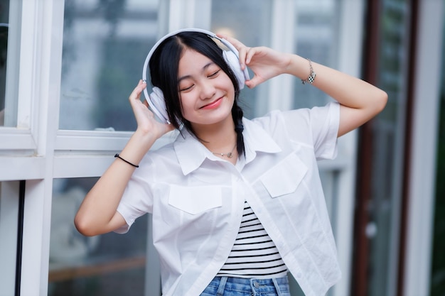 Photo heureux de sourires mignons asiatiques de jeunes attirantes mignonne petite fille portant des écouteurs sans fil blancs