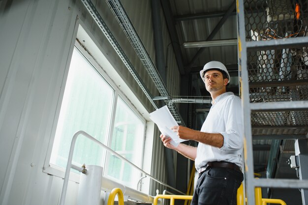 Heureux technicien industriel masculin à l'intérieur d'une usine