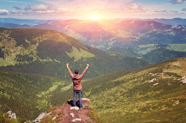 Heureux touriste debout avec sac à dos au sommet d'une montagne avec les mains levées Concept de réussite