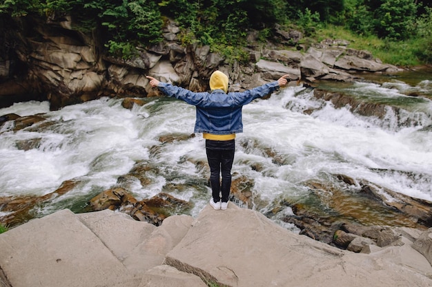 Heureux touriste masculin se tient le dos avec les bras levés à l'air frais dans la forêt